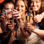 Group of partying girls clinking flutes with sparkling wine